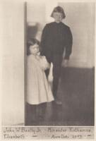 This photograph depicts two young children. A young female child stands slightly behind a wall, with her older brother behind her.