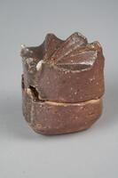 Flower shaped incesnse container consisting of two halves, which open horizontally, and fit together very precisely. Decorated with ash glaze, which gives the pottery a deep red color, deeper on the top and slightly lighter on rest of the container, with black as an accent color primarily on two sides of the container in a line going from the top of the piece to the bottom.  The top of the container is very dramatically textured is a symetrical series of ridges which create the petals and shape of the flower.