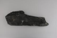 A flat piece of soapstone that serves as the base for Man Pulling Walrus. It has three holes where the figure and the seal attach.