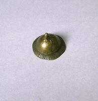 Dome-shape brass with a flared edge incised with vertical lines. There is a raised projection at the top of the object. 