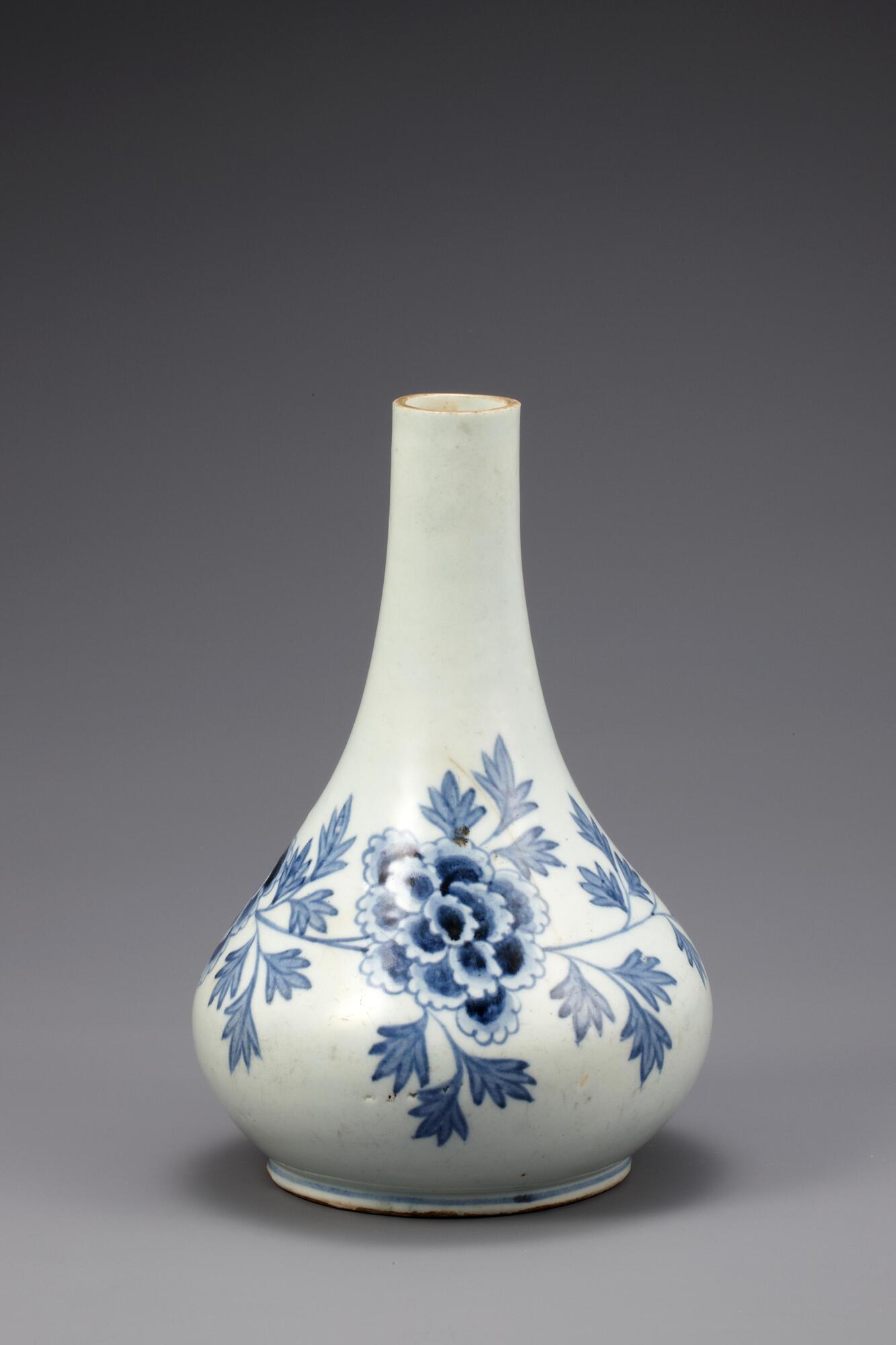 It has a long, thin neck and flat oval body. The wide foot is rather shallow but deeply recessed on the underside. The entire of surface is decorated with peony blossom design printed in cobalt blue sigment.<br />
<br />
This is a long-necked white porcelain bottle with peony sprays wrapping around the entire body. The white porcelain background is bright in colour, while the light and dark contrasts of the peony pattern give its flowers a three-dimensional appearance. There are sand spur marks on the foot, and on the outer base are incised symbols. Such marks are found in the waste deposits of kilns in Bunwonri, Gwangju-gun, Gyeonggi-do at the end of the 19th century. The mouth has been severed lost. This is a high-quality white porcelain bottle, with well sintered clay and glaze, but the rim has been severed and lost.<br />
[Korean Collection, University of Michigan Museum of Art (2014) p.179]