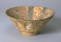 This Kashan style bowl from the Seljuk period in Iran features eight brown interior bands. The cobalt blue bands have white inscriptions in Naskhi-style calligraphy radiating from the center to the lip of the bowl. The exterior contains delicate floral stalk decorations. The presence of excrescences on the interior may determine that this bowl was used for waste.<br />
 
