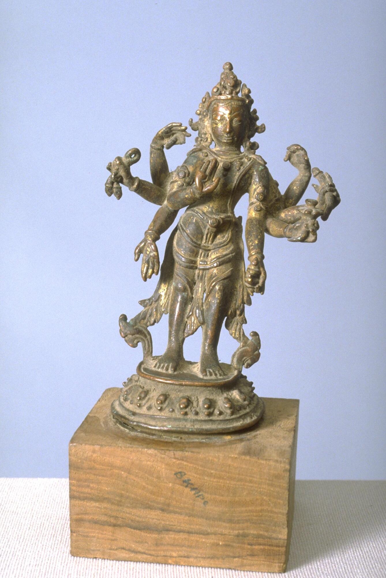 A small bronze figure of Amoghapasa, a Buddhist deity, made by the cire perdue (lost wax) casting method. The challenge to the caster is this case is the top-heaviness of the piece caused by the iconographical requirement for the image to have eight arms; in at attempt to provide some support, he arranging floating scarves to drape all the way to the lotus pedestal.