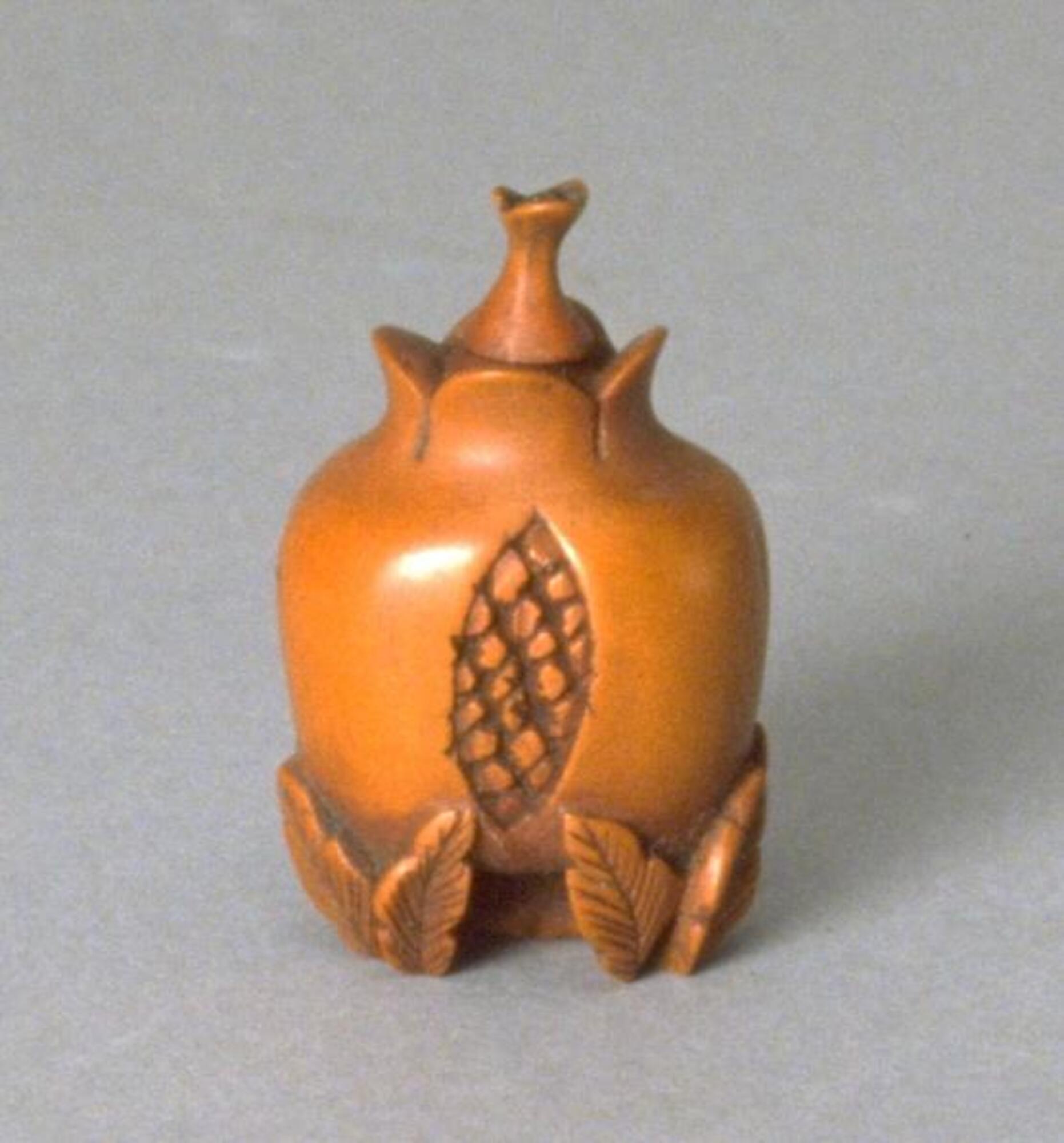 &nbsp;A golden wood snuff bottle in the shape of a pomegranate with pairs of leaves at the base.