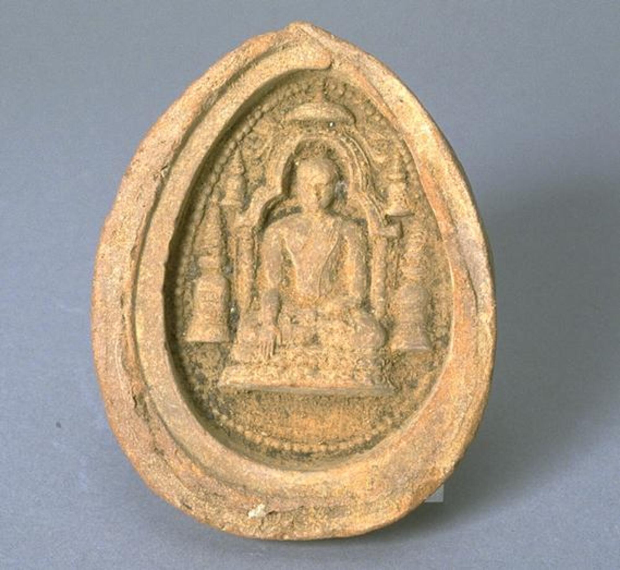 This clay votive plaque depicts the Buddha in the gesture of “calling the earth to witness."  He is shown here surrounded by five stupas, or reliquary monuments.