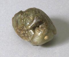 A brown and green nephrite jade snuff bottle in the shape of a duck that is curled upon itself. Carved on the wings are feathers.