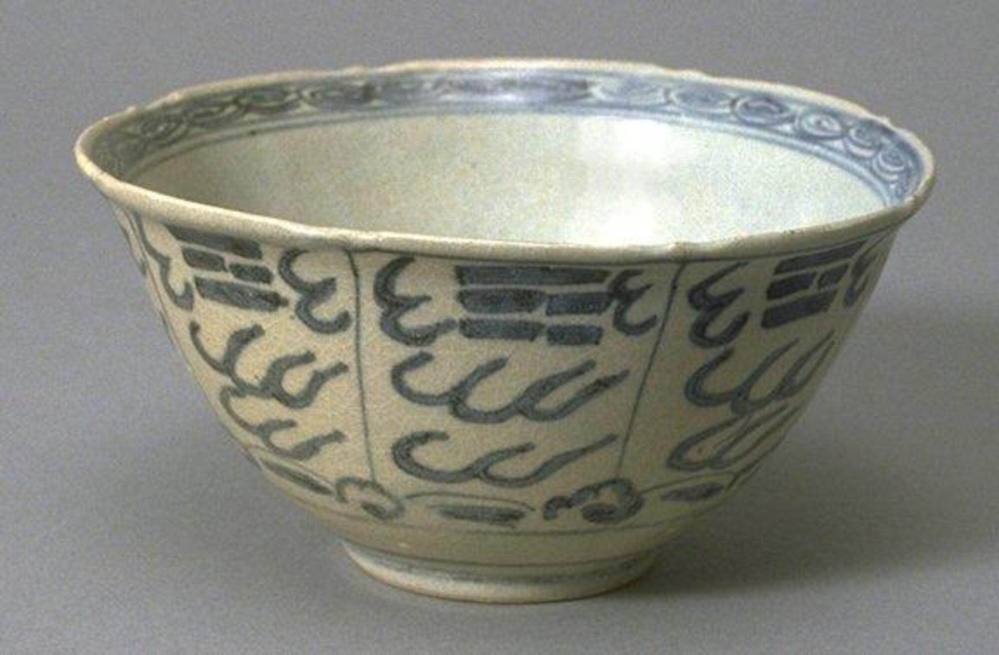 A small hemispherical bowl with everted rim on a straight footring, decorated with underglaze cobalt blue. The exterior depicts the <em>bagua, </em>or eight trigrams of the I Ching, around the rim, surrounded by stylized clouds with silk-worm pattern band around the interior rim. The bowl is covered in a clear glaze. 
