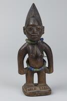 Standing female figure on a square base. The hands are at the sides and the figure has prominent breasts. Around the neck and waist there are strings of glass beads. Each cheek has three vertical grooves, while the hair has a rounded comb-like shape with vertical grooves along the upper area and a chevron pattern below. 