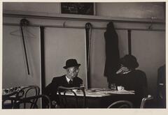 Two men wearing black hats seated at a dining table in a restaurant.