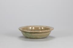 <p>Many lobed dishes of this kind were produced in the 13th century. This dish was shaped by using a mold. The flat and wide base, which has been pared down, has three quartzite spur marks. Glaze has been applied even down to the inner base and rim of the foot, but is thick and opaque. Colors of the inner and outer surfaces di er, with that of the inner surface being darker.<br />
[<em>Korean Collection, University of Michigan Museum of Art </em>(2014) p.115]</p>
This flower-shaped celadon bottle with impressed decorations has a flat bottom and slanting sides. The form of the vessel was produced using a mold. The thick wall gives the bowl a rough appearance. The everted mouth forms a flat rim in the shape of a flower. A green glaze is applied to the entire surface.