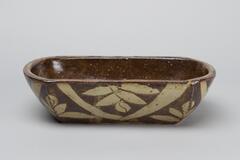 Brown oblong bowl with a white leaf pattern.
