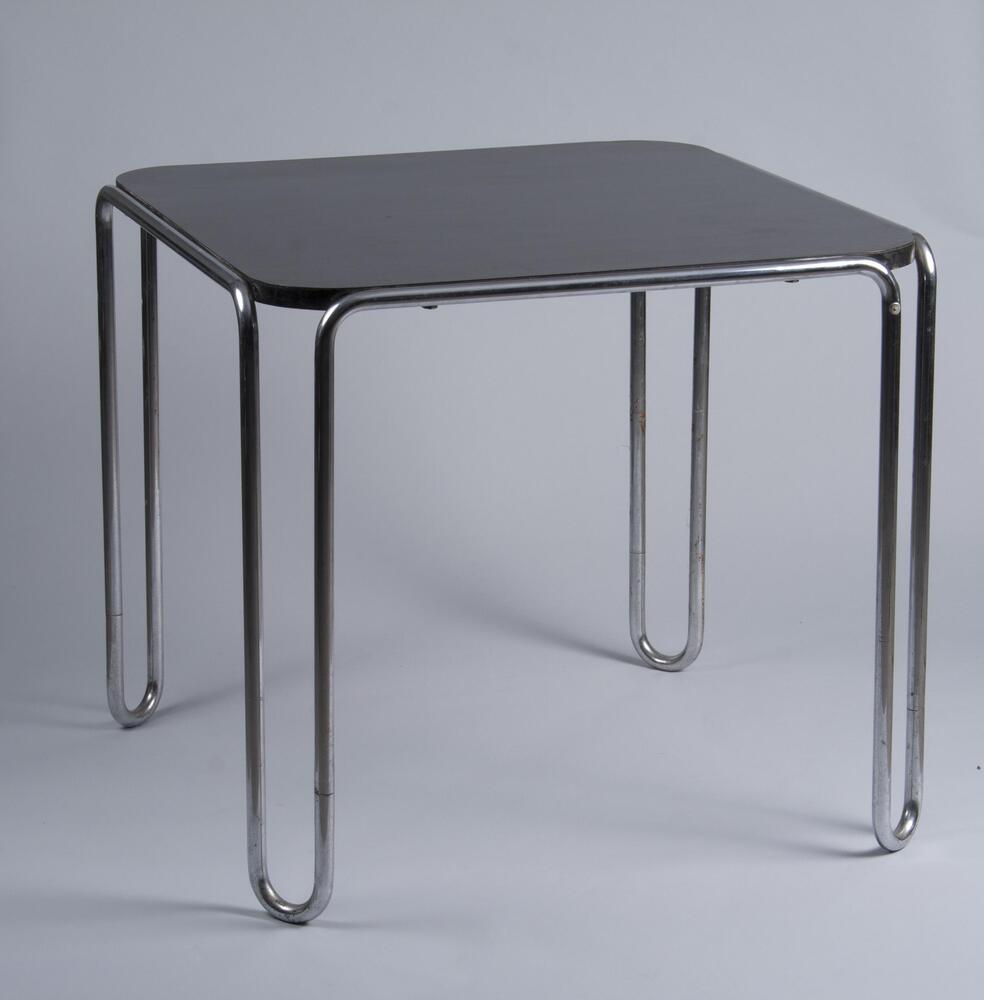Black square table mounted on a frame of continous steel tubing that curves down at the corners to form bowed legs.