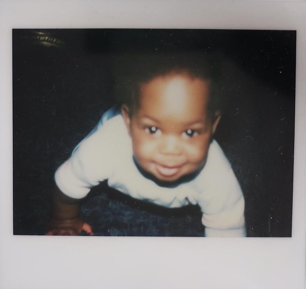 <span style="font-size:12pt"><span calibri="" style="font-family:">A smiling baby crawling towards the camera wearing a white shirt. The background is dark and the baby is in soft focus.</span></span>