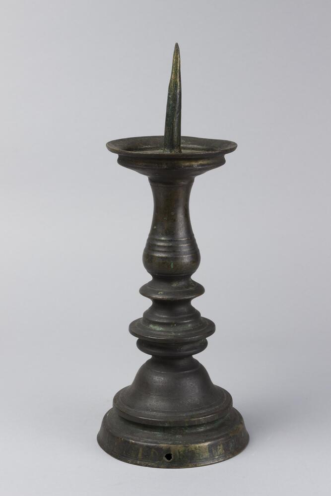 Tall candlestick with pointed top and rounded bottom.