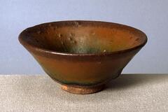 A deep, conical bowl on a straight foot ring, covered in a thickly applied dark iron-rich black glaze with lighter russet-brown hare's fur markings (兔毫盏 <em>tuhao zhan</em>).  