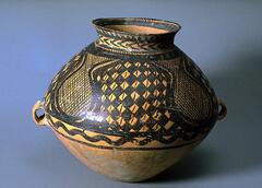 A light reddish-buff earthenware <em>guan (</em>罐) jar with a wide globular upper body and conical lower body on a narrow flat base, a tall wide neck and a flaring rim. Two diametrically opposed lug handles are located at the waist. The upper half of the body is painted with black pigment to depict four gourd-shaped areas containing a network pattern. The negative space between the gourd-shaped areas contains a checkerboard pattern confined between solid band borders, with a lobed line border below, and one final solid black band at the bottom of the design. Around the neck are bands of herring bone, sawtooth, and hatch mark patterns, and additional hatch marks and solid bands toward the interior.  