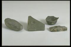 Pieces of a gray stone ax or agricultural tool.