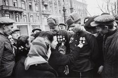 Two soldiers are surrounded by a crowd of civilians who admire the soldiers&#39; medals pinned to their breasts.