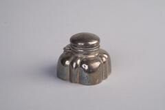 A square, silver inkwell with rounded corners.