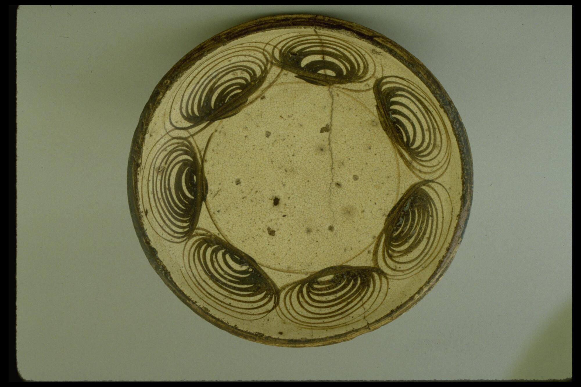 This plate has durable body and protective glazed surface. Seven brown ring-like patterns (said to be modeled after horse eyes) decorate the inner rim of the large plate. The outermost edge is ringed in brown.