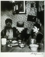 This photograph shows a man and woman at a dinner table. The man is covered in coal dust from his work in the mines.