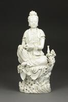 Guanyin is seated in a posture of royal ease on a decorative chair with a small table holding a small jar and three scrolls. Her left arm is resting upon her left knee while her right arm is crossed in front of her holding another scroll. She is wearing a robe, a necklace, and her eyes are closed,