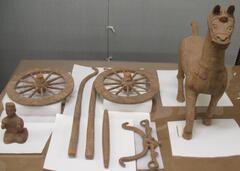 A pottery sculpture of a horse and the makings of a cart.
