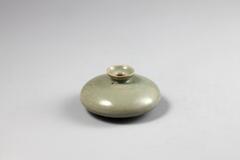 It has a flat round shaped-body and a rim in the shape of a hemisphere. The foot is small and low-rising. The shoulder is adorned with cloud.<br />
<br />
This celadon oil bottle has a short neck and round body. A cloud design is incised on the shoulder of the bottle. The rim of the foot has three refractory spur marks. This is a good example of a Goryeo celadon oil bottle in terms of both glaze and form.<br />
[<em>Korean Collection, University of Michigan Museum of Art </em>(2014) p.130]<br />
&nbsp;