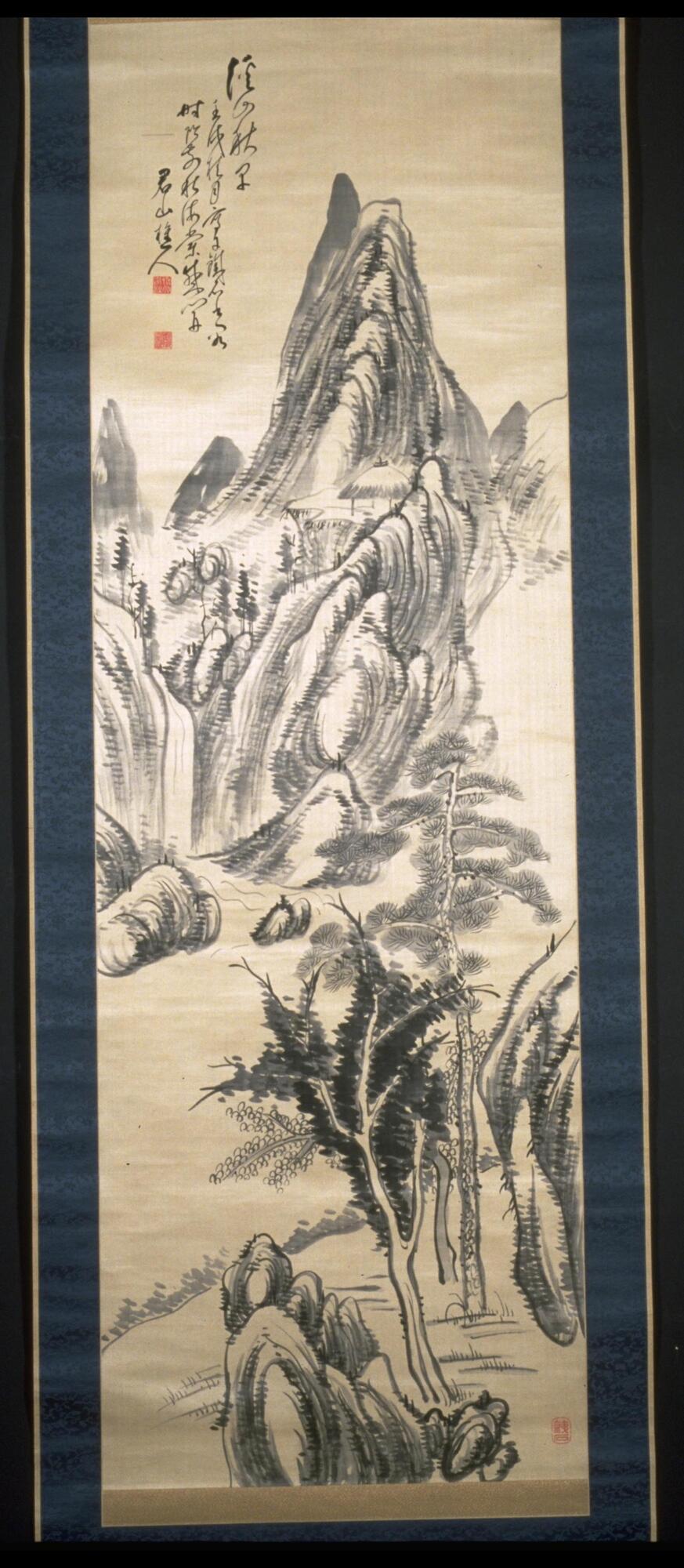 There is a mountain in the background with a waterfall pouring out of it and flowing into a river. On the opposite shore of the mountains, there are rocks and trees. There is an inscription and seal in the top left corner of the hanging scroll. The hanging scroll is bordered with blue.
