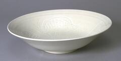 White porcelain bowl with carved inside and smooth outside.  A ring is carved along the inside rim, and below are quails alternating with grasses.