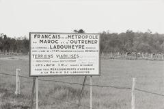 A photograph of a real estate sign in French. The sign stands in front of a fenced in rural field. A forest is visible in the background.