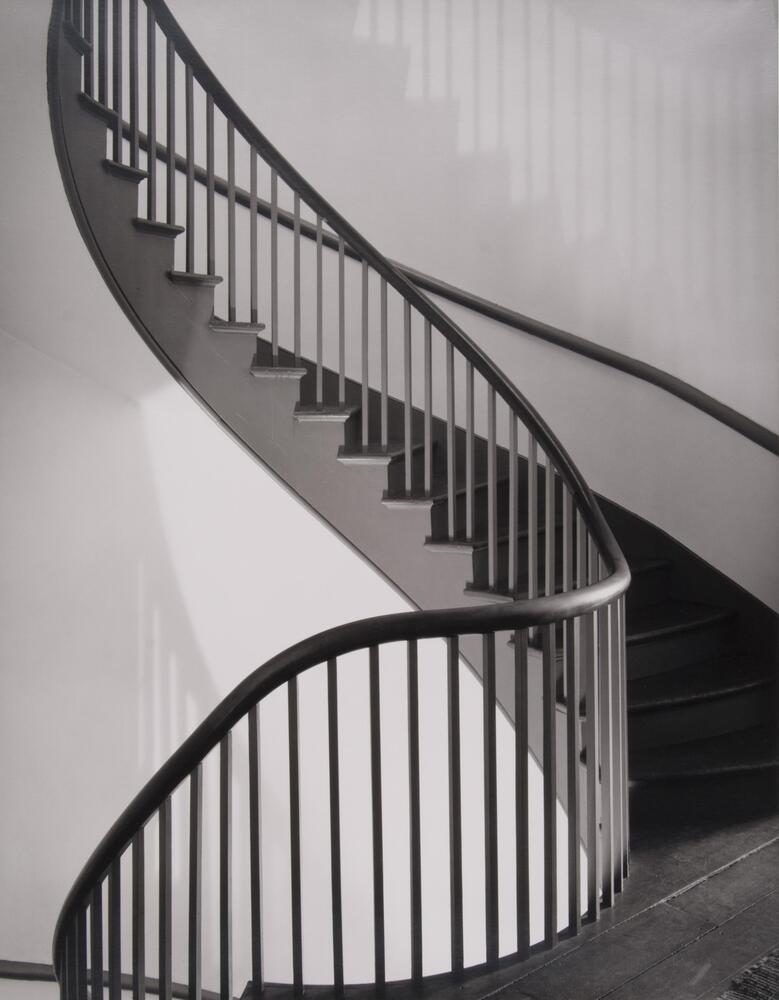 A winding staircase in between floors. Curves from the lower left up into the upper left, almost like a large "J" curve.