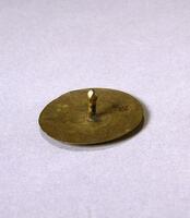 A flat, circular brass disc with a short, central post. 