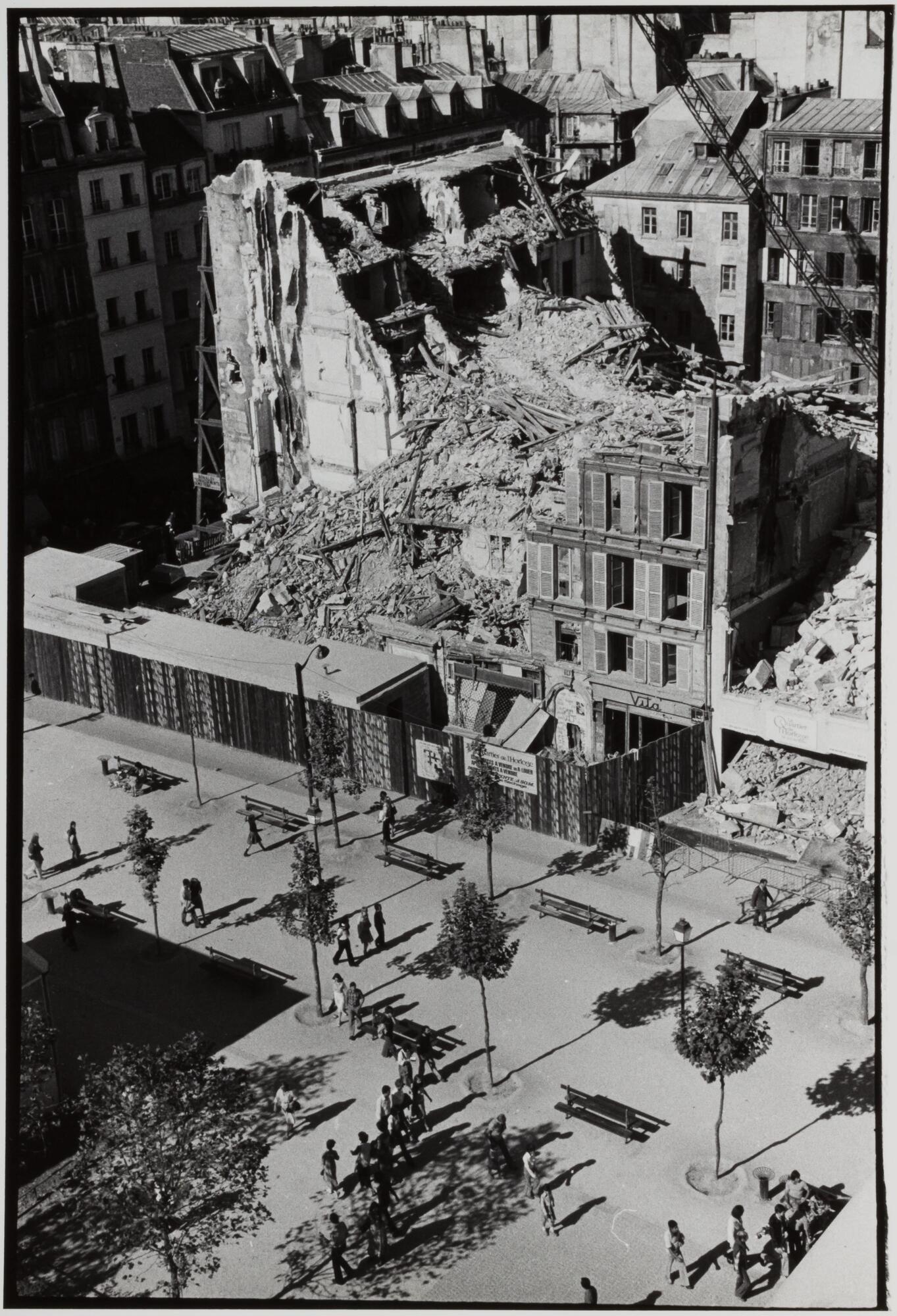 A demolished building in ruins on a city street. There is pavement and trees below.