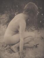 A nude female figure crouches in the sand with her right hand extended toward the ground. She is turned away from the camera, looking at vegetation in the background.