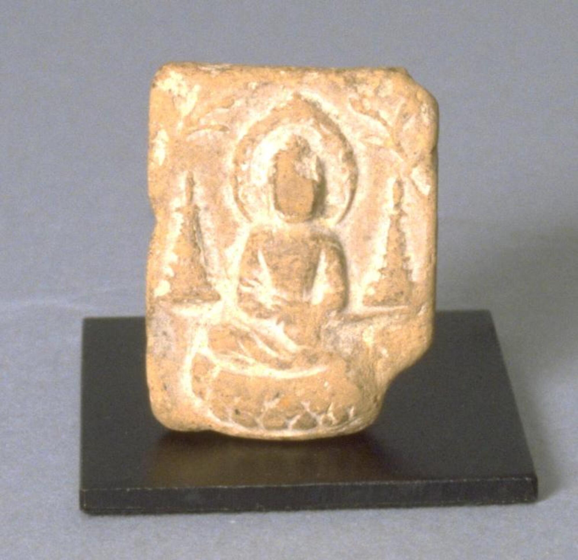 A small, thin, molded clay plaque with a bas-relief scene.