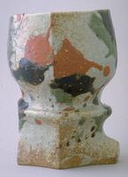 Asymmetrical vase with red, black, green, splotches of design on off-white glazed ground.