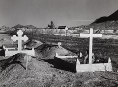 A cemetery with mineworks in the background.