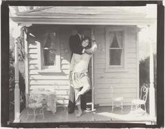 A girl and a man standing in front of a dollhouse.
