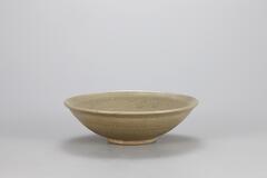 This is a conical bowl that rests on a footring, with a slightly everted rim, covered in a gray-green celadon glaze.