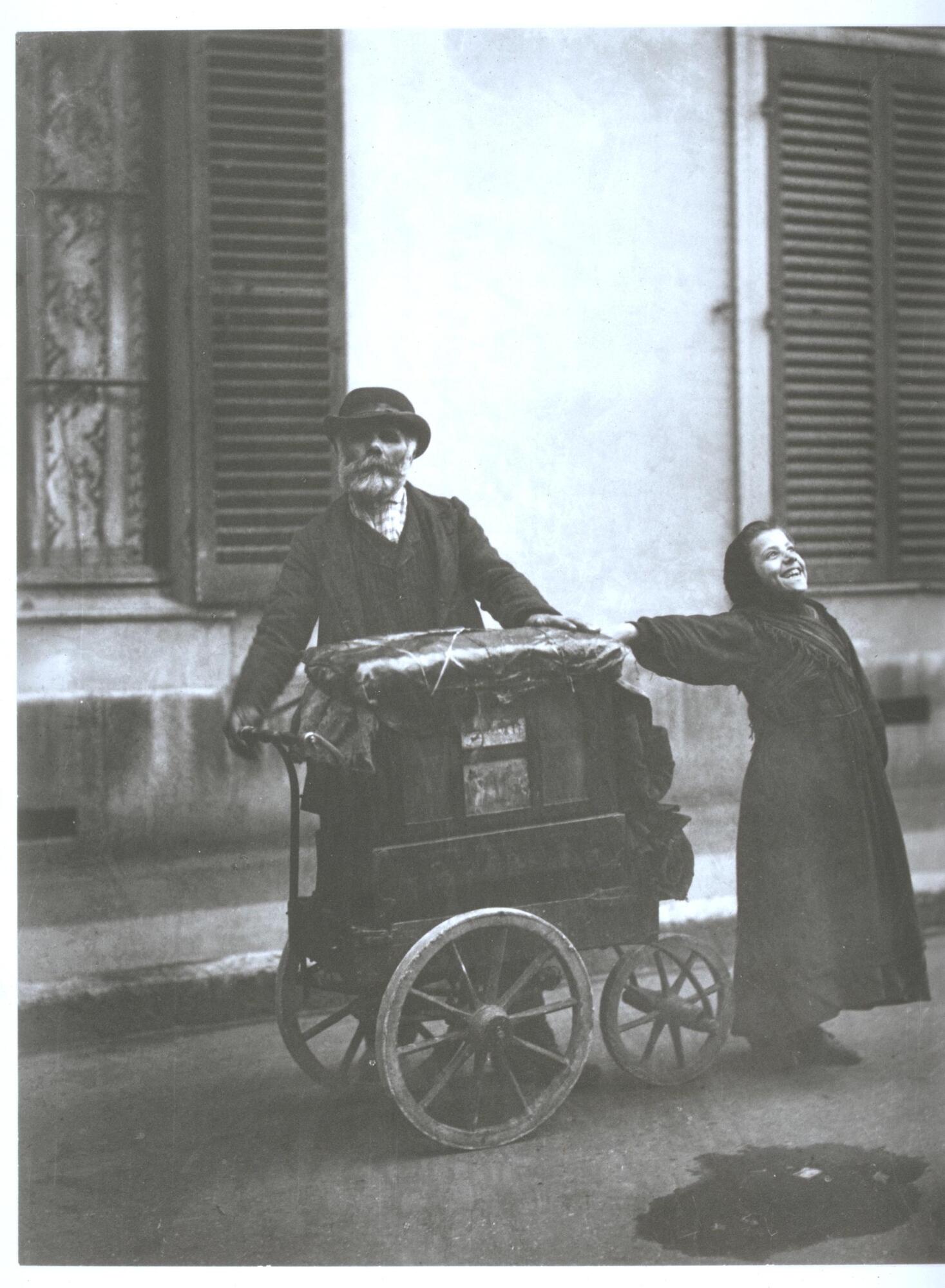 An organ grinder and a young girl perform on a Paris street.