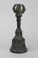 This is one of a pair of Javanese bells.  A talon-like vajra sits atop the bronze handle.  Lotus petals decorate the base, and the faces encircling the the bell above them depict Prajnaparamita, the bodhisattva aspect of “Perfection of Wisdom.”
