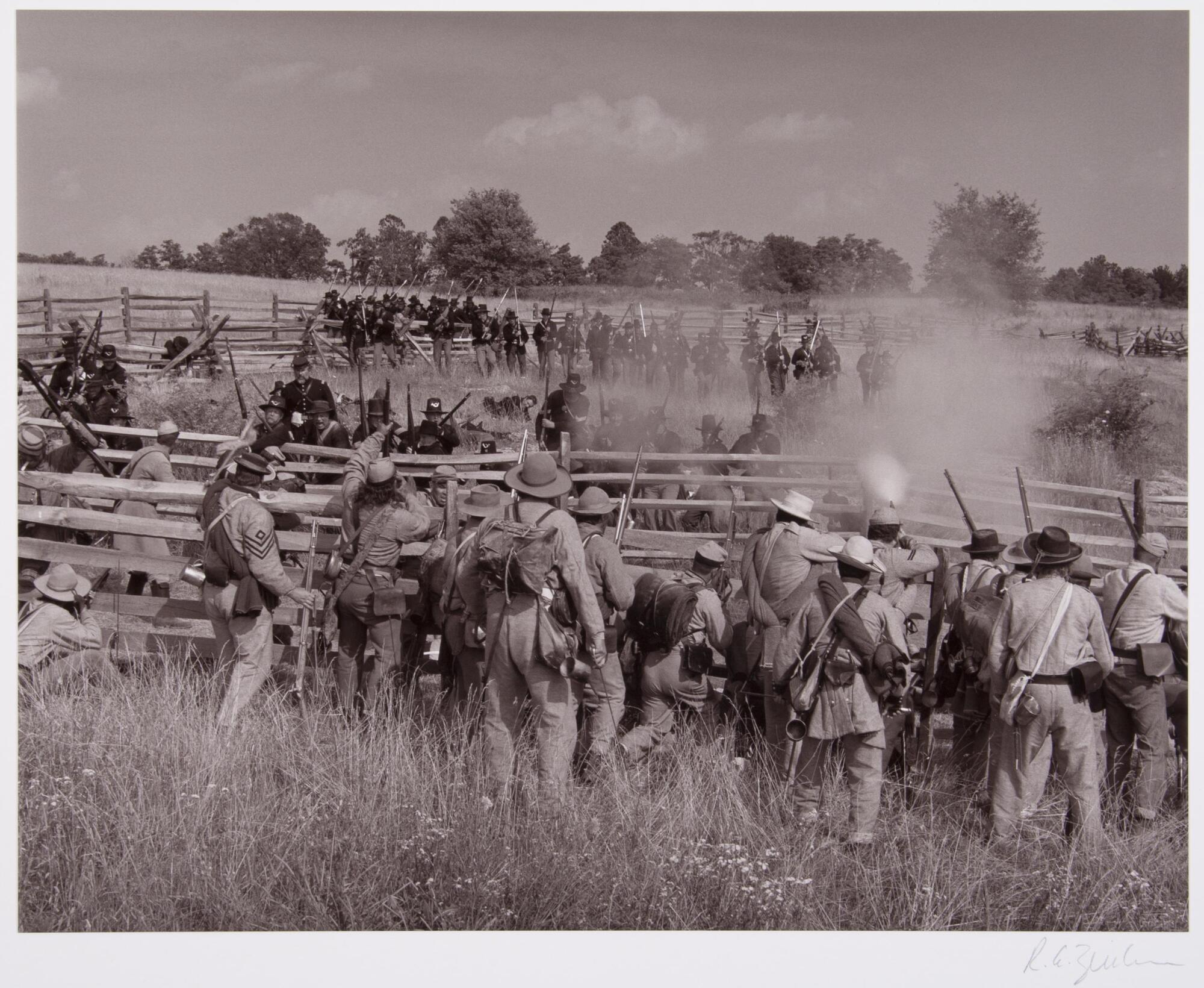 Army Reinactment. Two sides of the battle are fighting in a field with a fence between them.