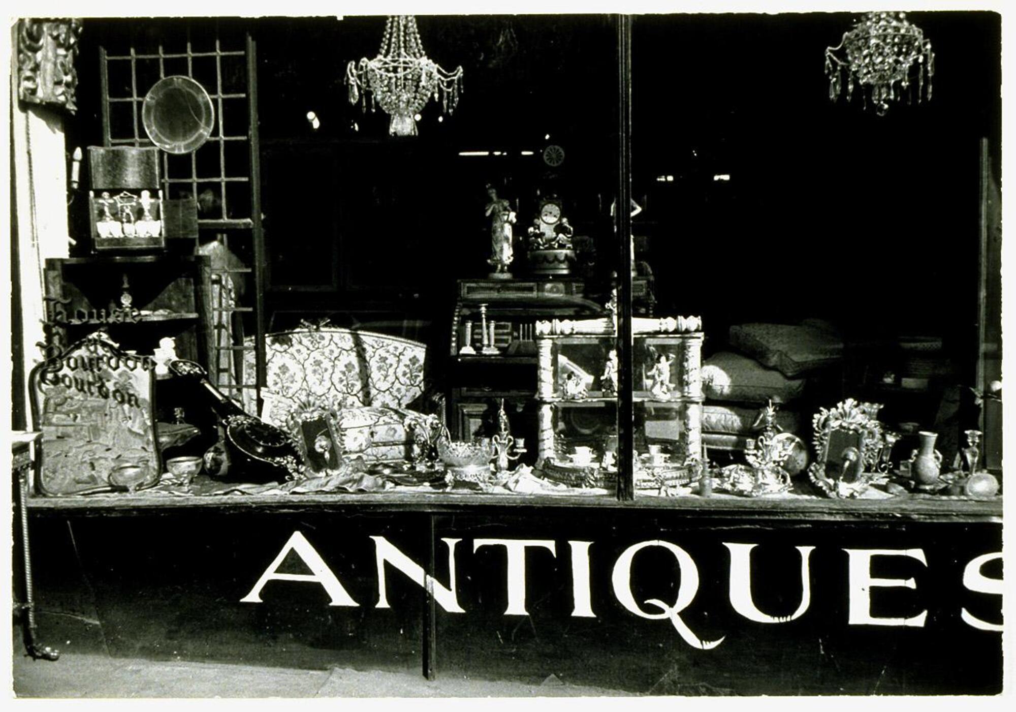 This photograph shows a view of an antique store's front vitrine, featuring a variety of decorative objects and furnishings.