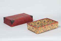 One box with a lid completely encompassing it. The lid has a red and black exterior and an interior with a geometric design in orange and blue hues. The box has the same geometric design on the interior and exterior.
