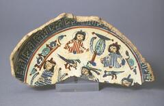 This Mina'i ware bowl fragment displays well preserved base decorations. Five figures, two birds, a tree and a rim of Kufic insciptions float on the interior, while the exterior exhibits alternating red and cobalt symbols. The bowl is made with a pink-tan paste and a glossy all-over glaze. Ivory, red, cobalt, turquoise, black, pink and brown paints are used to create vibrant imagery.