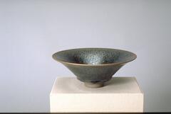 Footed stoneware bowl with tenmoku 'oil spot' glaze and unglazed foot.  The bowl black tenmoku glaze blends to brown at the flared rim.