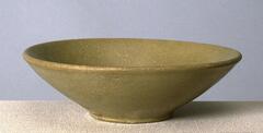 A conical bowl with a direct rim on a footing, covered in a gray-green celadon glaze with a very fine craqueleur.