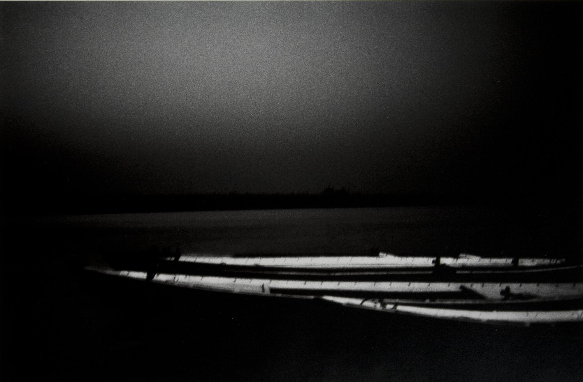 A black and white photo of three canoes.