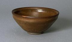A deep, conical bowl on a straight foot ring and subtle rim articulation, covered in a thickly applied dark iron-rich black glaze with profuse lighter russet-brown hare's fur (兔毫盏 <em>tuhao zhan</em>) markings.  